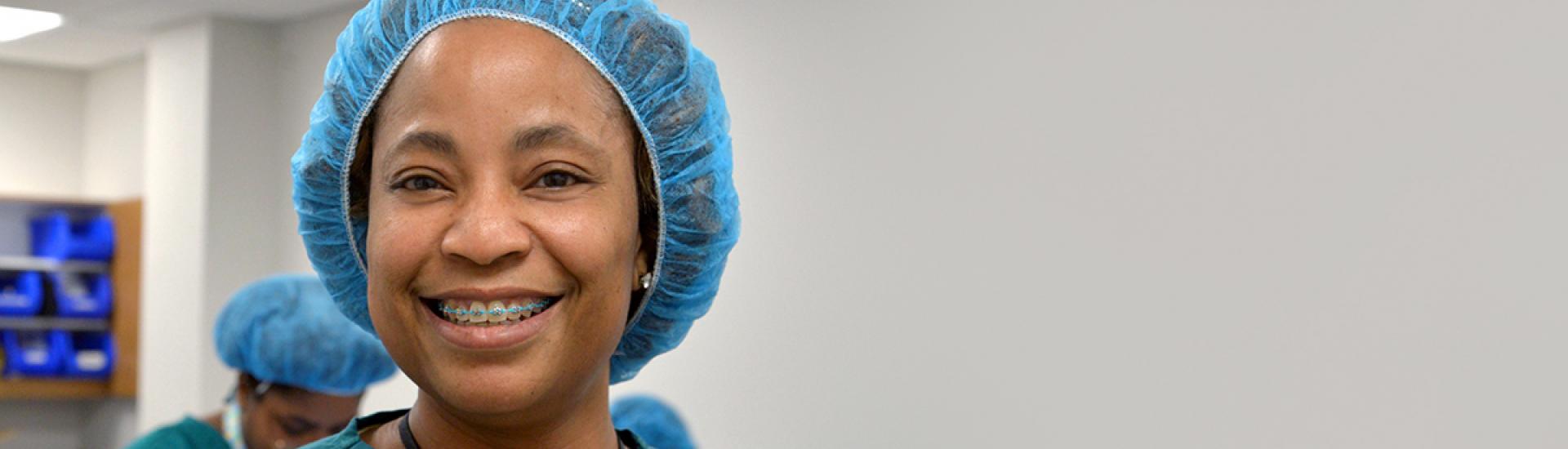 Student in scrubs hat smiling in central sterile processing classroom. 