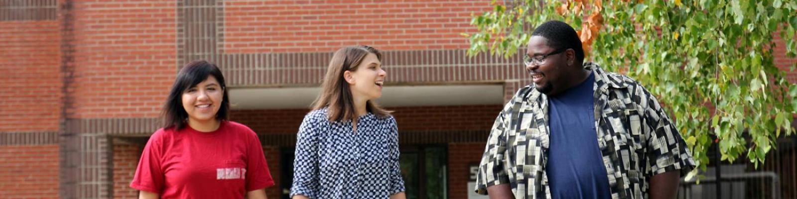 three smiling students walking on campus